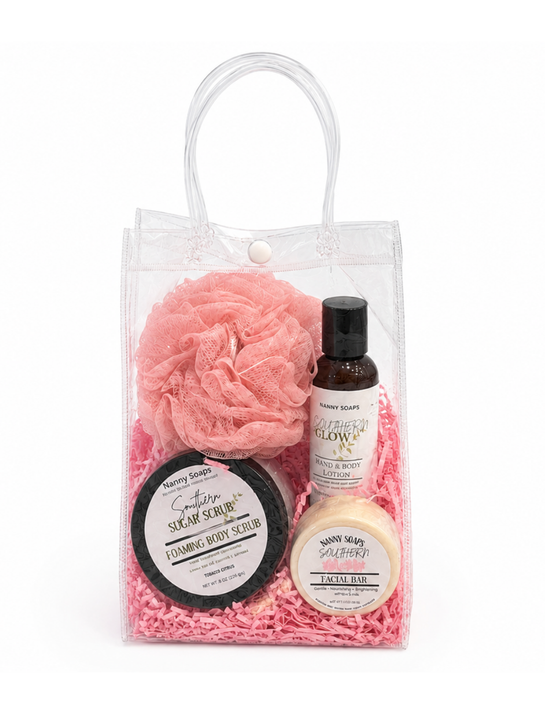 Set of beauty products including a pink scrub ball, black scrub, and bottles in a clear bag on a white background