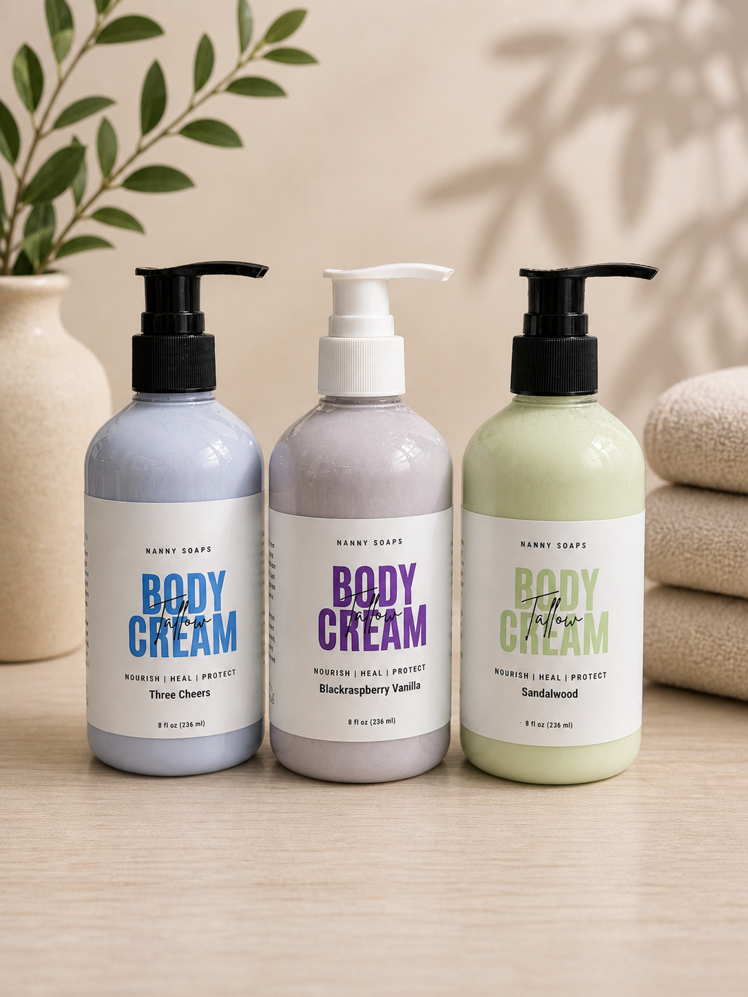 Three bottles of body cream with pump dispensers on a wooden surface, with a neutral background.