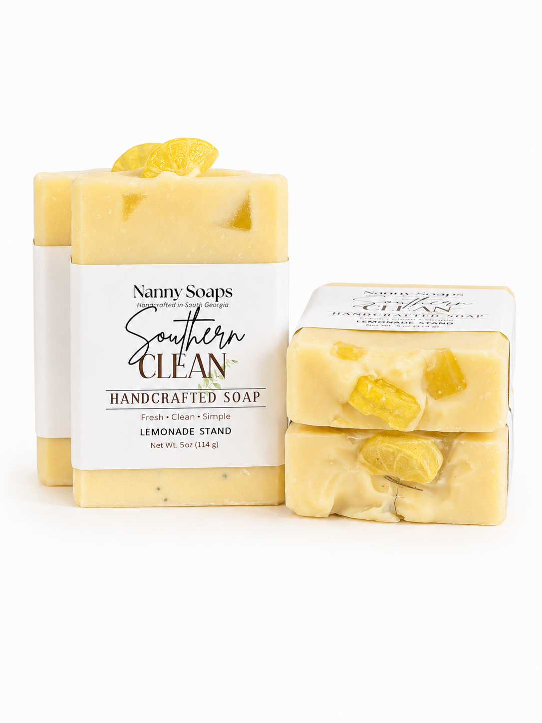 Two bars of yellow soap with visible lemon pieces and a branded label on a white background.