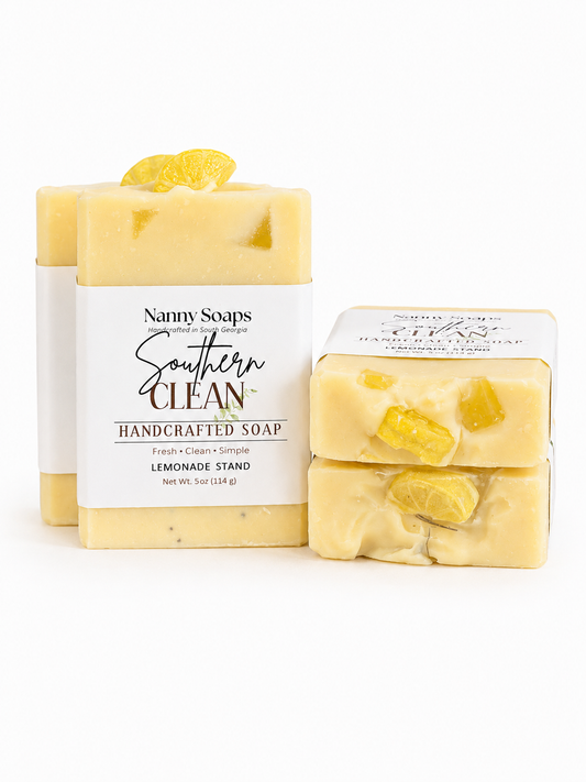 Two bars of yellow soap with visible lemon pieces and a branded label on a white background.
