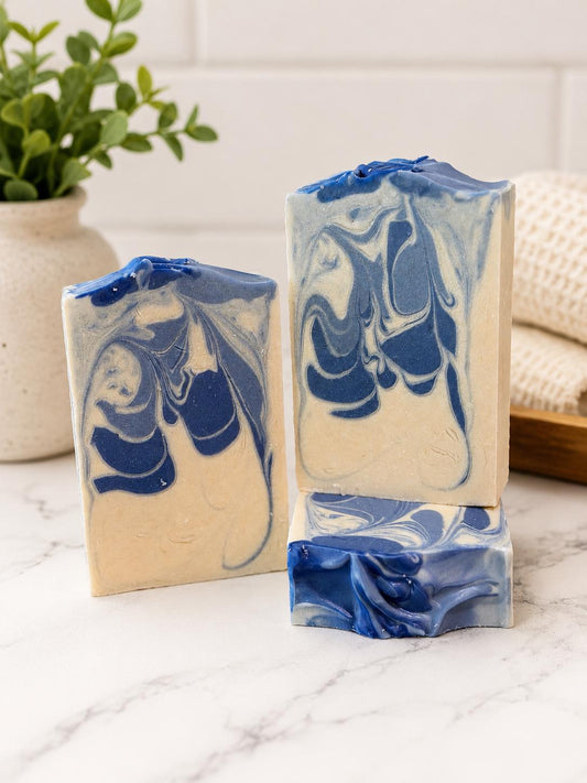 Three bars of soap with blue and white marbled design on a marble surface.