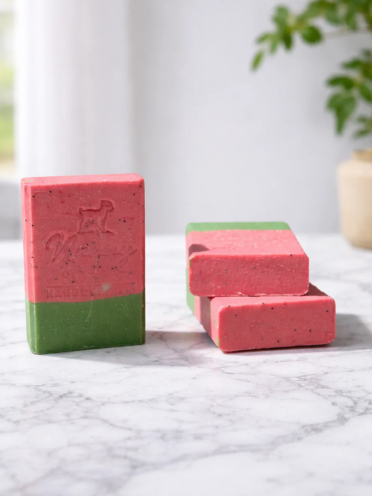 Three rectangular bars of soap that look like a watermelon, with a pinkish red top speckled with black and a strip of green at the bottom